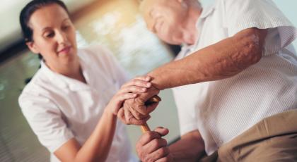 Physio holding hand of old man with walking stick