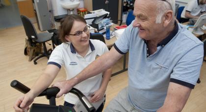 A prehab physio helps a patient exercise