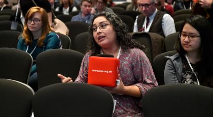 A woman holding a CSP mic asks a question at our annual conference